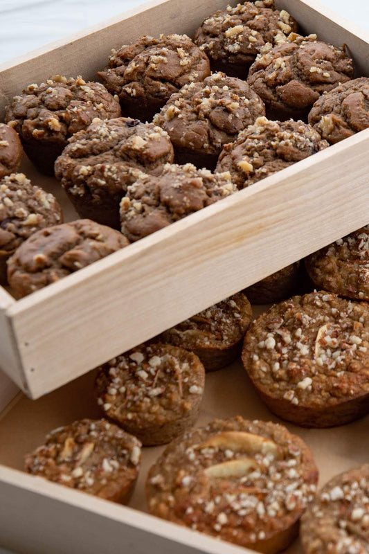 Assorted muffins in a wooden tray.