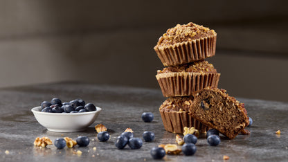 A stack of blueberry muffins and a bowl of blueberries