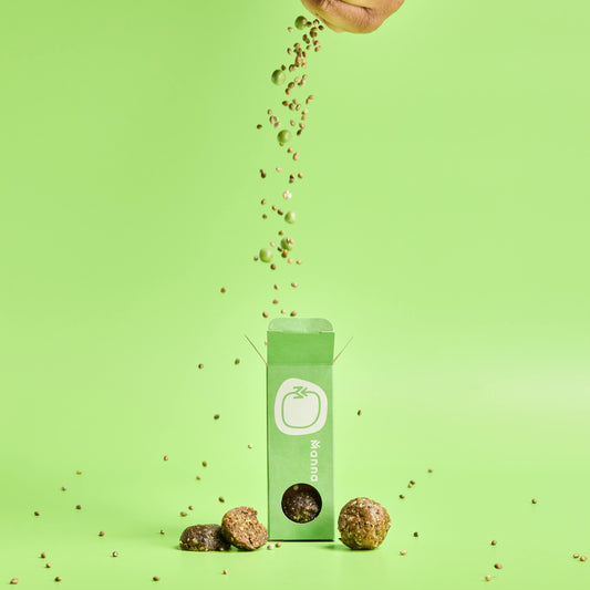 Energy balls being poured with seeds and Manna's branded packaging against a green background